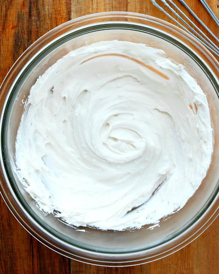 Whipped cream in a bowl on a board.