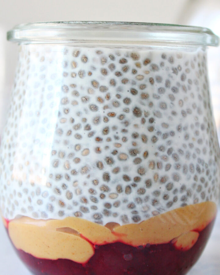 Jam, peanut butter, and chia pudding in a jar on a board.