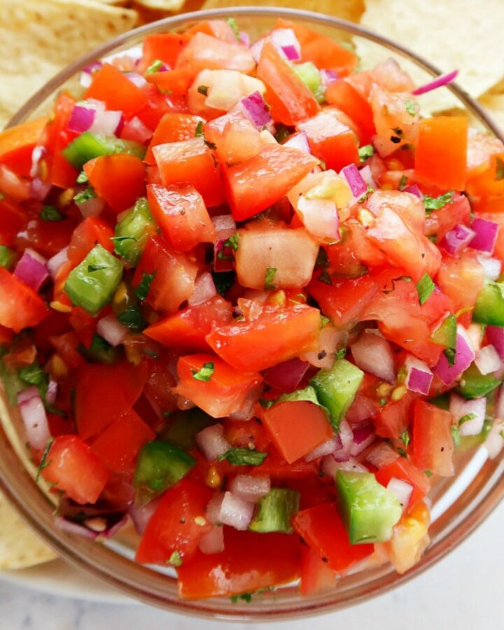 Pico de Gallo in a bowl with chips on a plate.